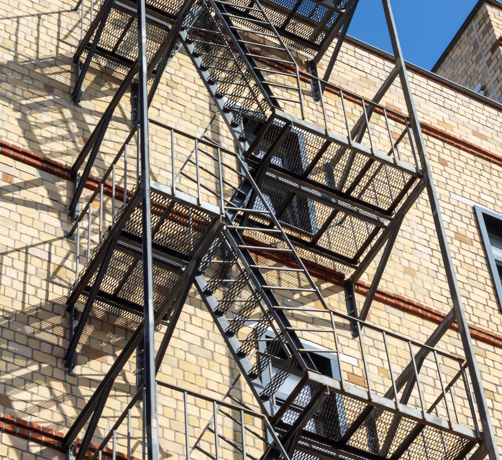 Fire escape hangs from brick buildings facade in city skyline
